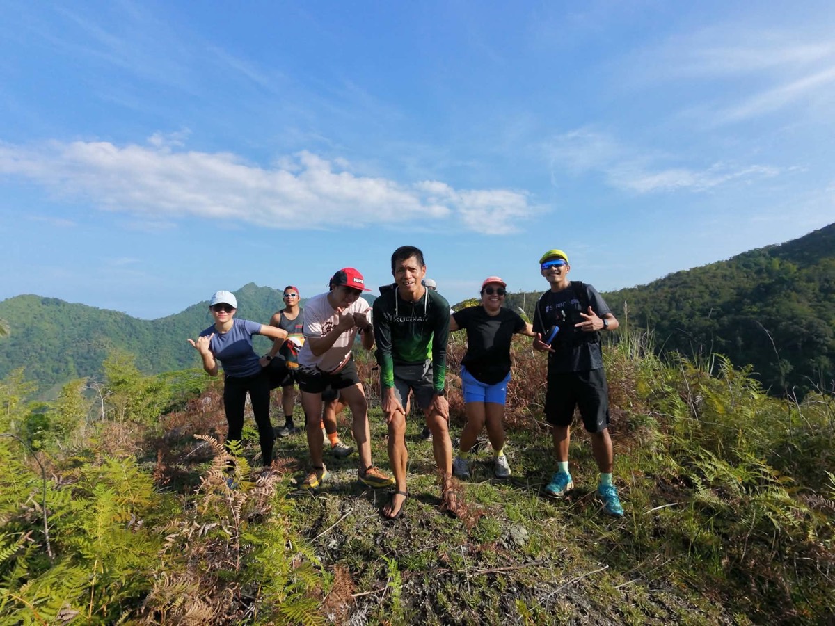 Trail runners posing and smiling on a ridge top